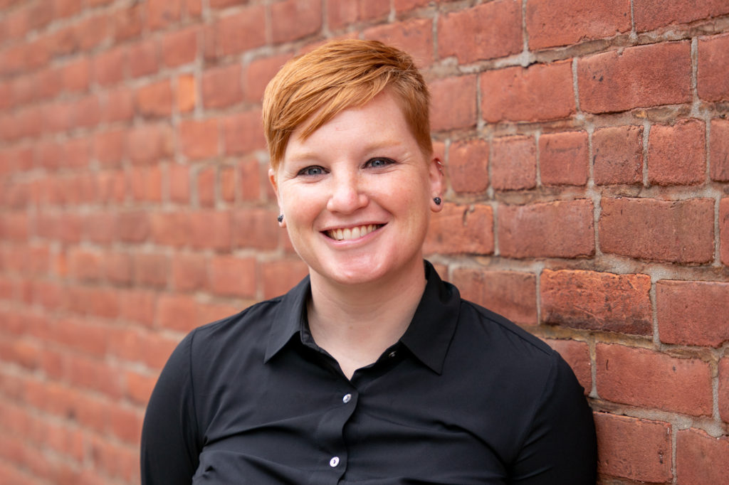 White woman with short red hair smiling at camera
