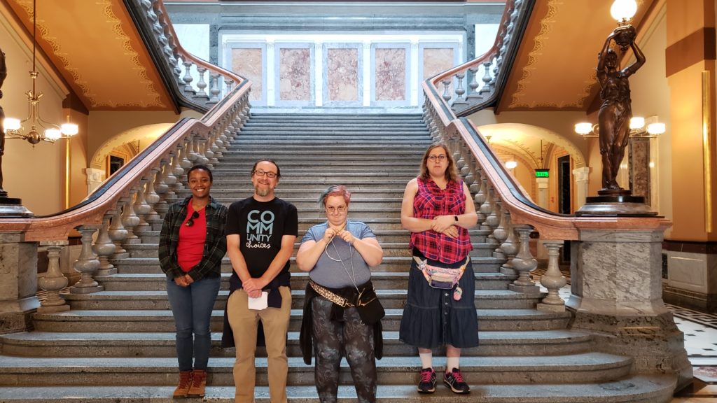 2 self-advocates and 2 staff stand on stairs at advocacy day at the capitol