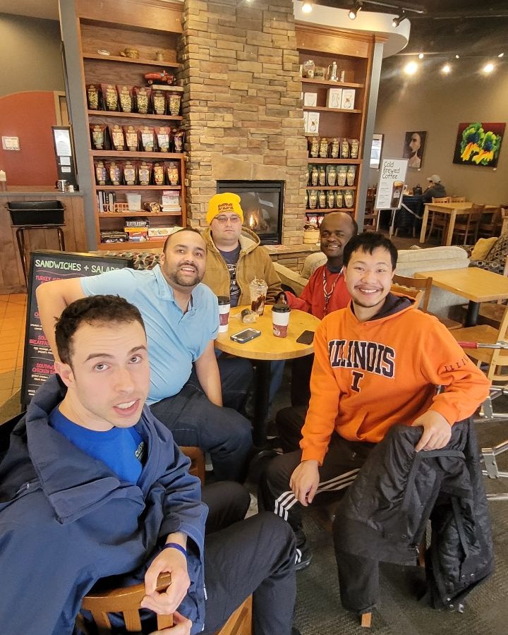 5 men in coffee club pose for photo around a table at a restaurant