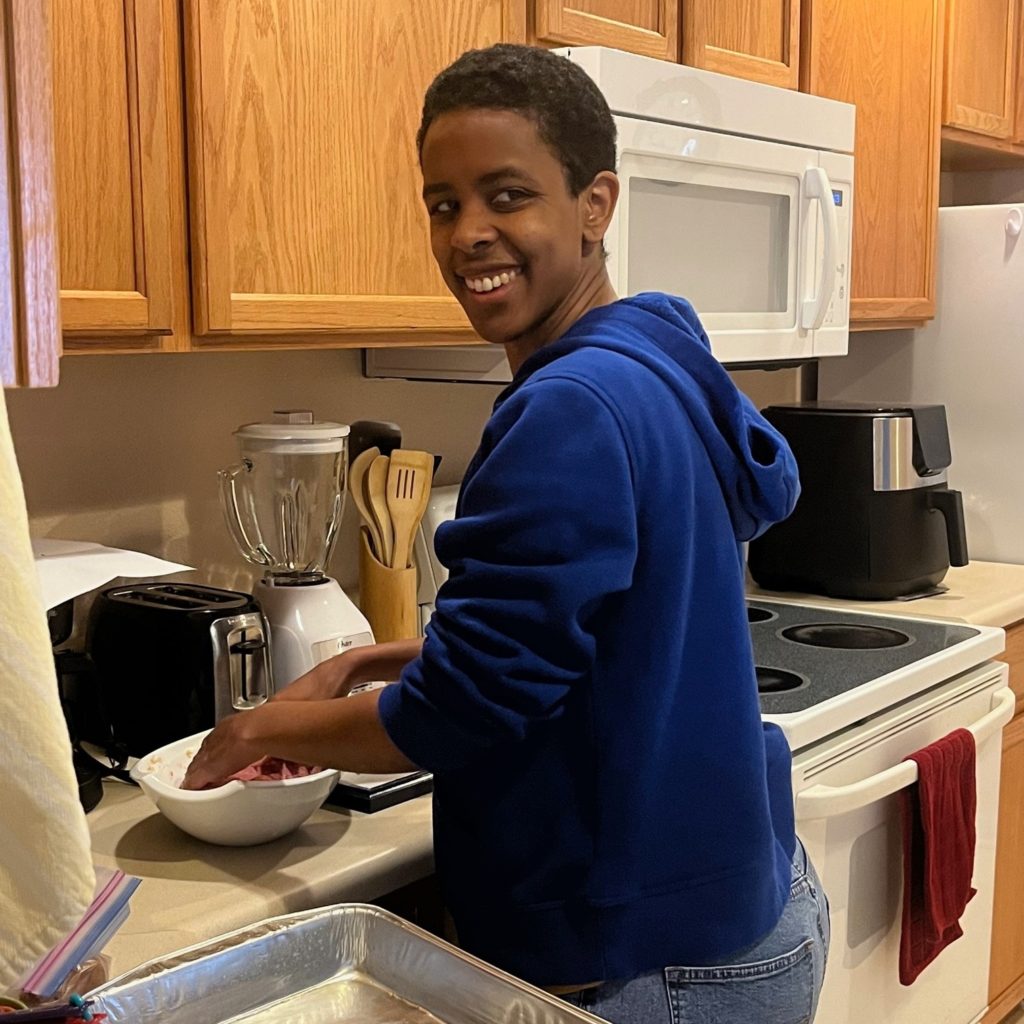 Black woman with short hair uses bowl to cook food.