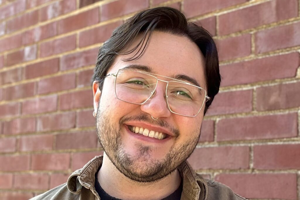 Photo of a white person with glasses, short dark hair and a closely cropped dark beard - smiling